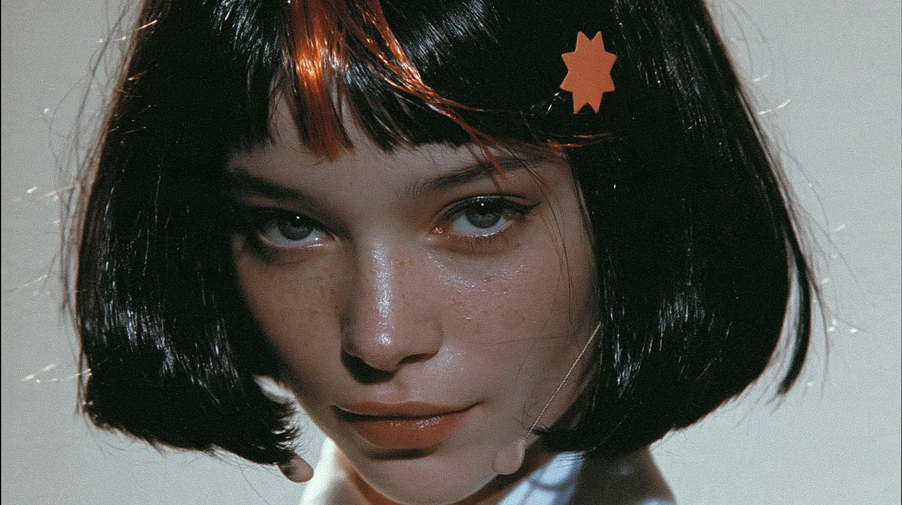 close-up portrait, head and shoulders, of a young woman with a glossy black blunt jaw-length bob with heavy bangs and one clay-orange streak through the bangs, a small flat clay-orange eight-pointed star hair clip, a…