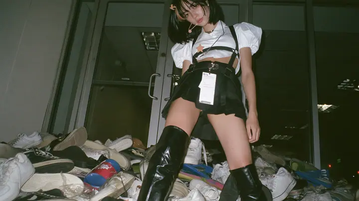 a pile of sneakers and slides outside the glass door of a startup office in North Beach at night, a sign-less door, a young Caucasian American woman with pale skin and light freckles, a glossy black blunt jaw-length…