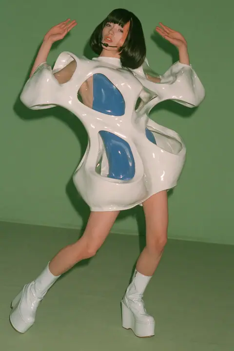 Y2K high fashion editorial, a 2001 couture magazine story: full-length shot, head to toe with the feet in frame, of a young Caucasian American woman with pale skin and a glossy black blunt bob with heavy straight…