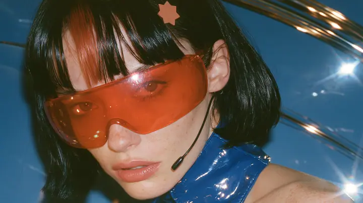 Y2K high fashion editorial, a 2001 couture magazine story: a Caucasian American woman in her mid-twenties with pale skin and light freckles, a glossy black blunt jaw-length bob with heavy straight bangs and one…
